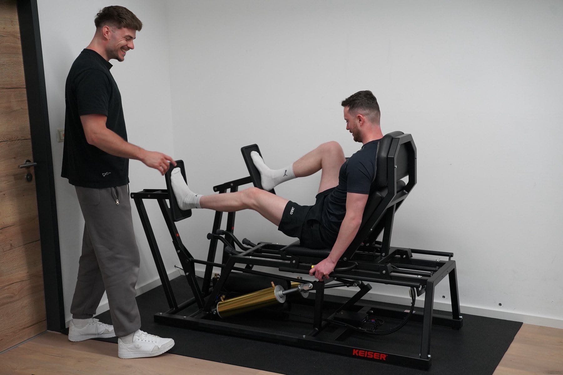 Training an der Beinpresse, der Therapeut steht daneben und leitet an