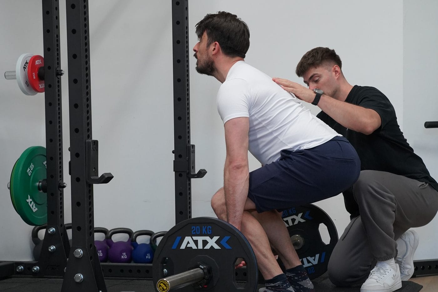 Der Therapeut korrigiert die Rückenhaltung in der Startposition des Kreuzhebens