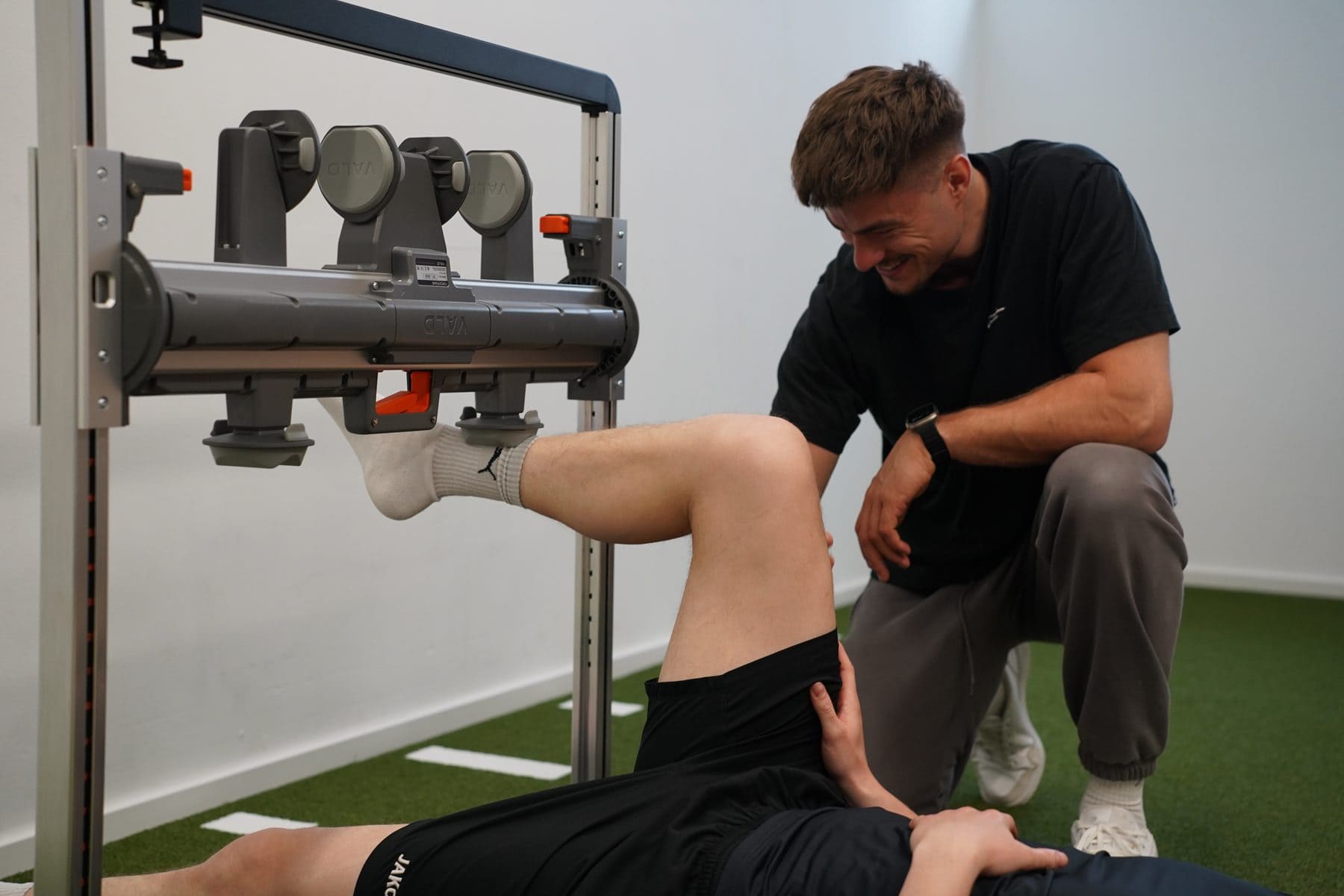 Kraftmessung am Knie im VALD ForceFrame, der Therapeut prüft die Position