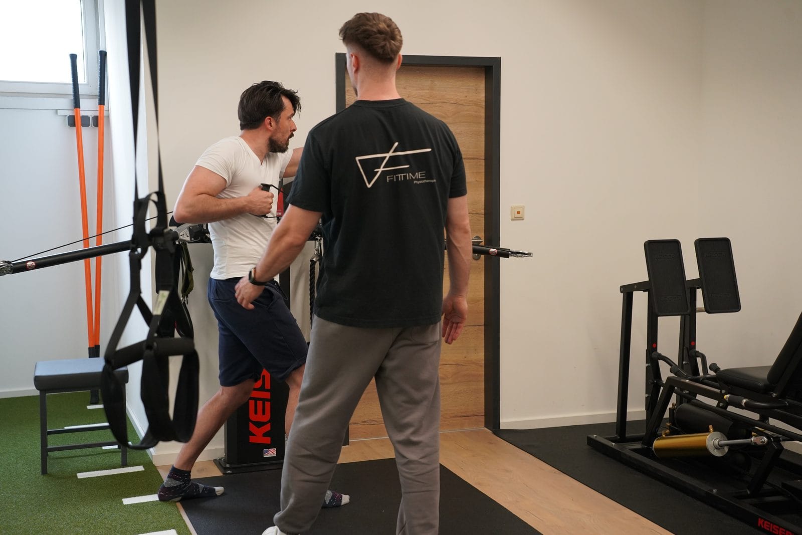 Training am Seilzug, der Therapeut begleitet die Übung