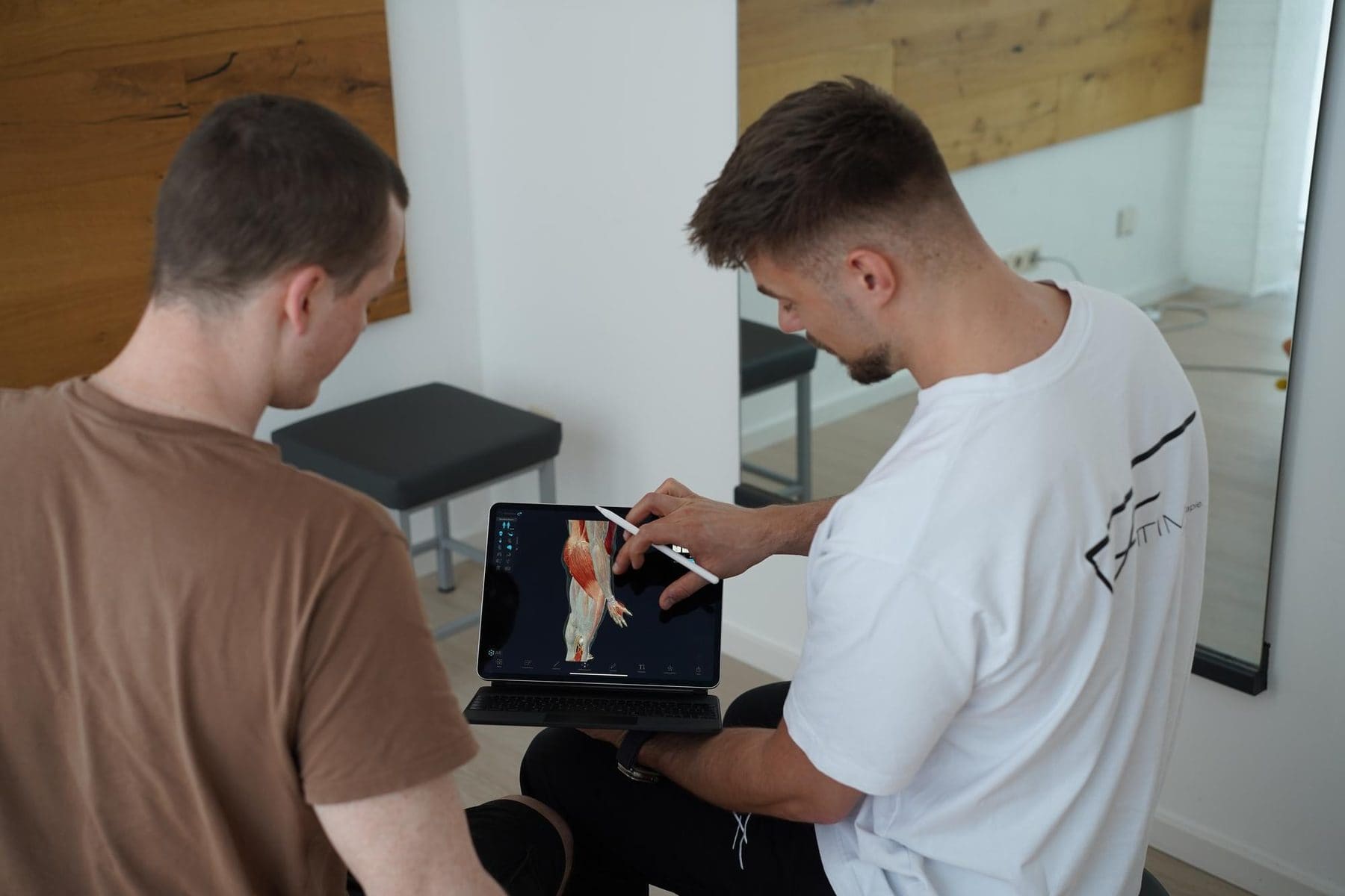 Erklärung am Tablet mit Anatomie-Modell im Behandlungsraum